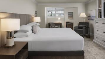 A modern hotel room with a large bed, bedside lamps, a desk, and a chair.
