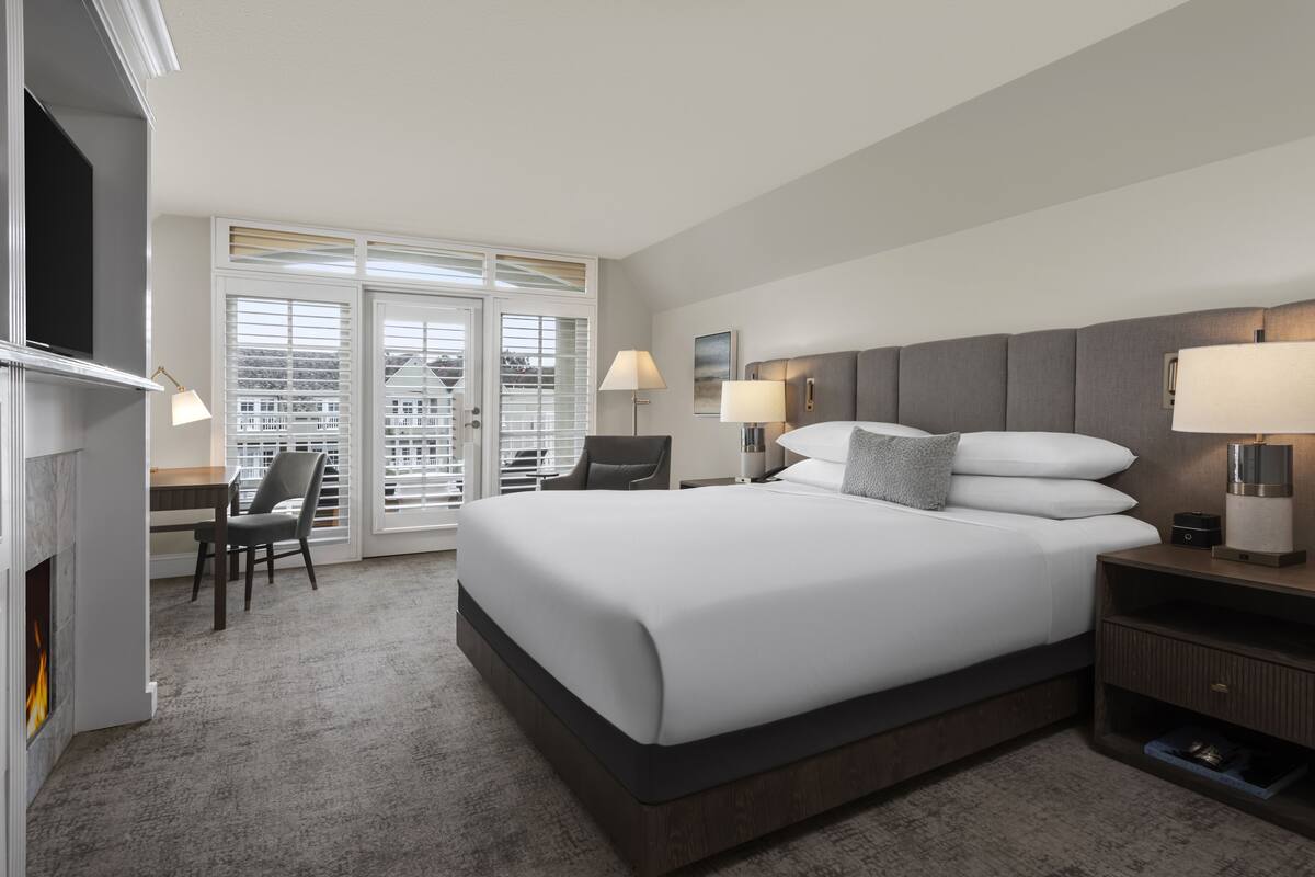 Una habitación de hotel moderna con una cama grande, un escritorio y un televisor.