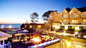 A hotel with outdoor seating areas, a pool, and a view of the ocean.