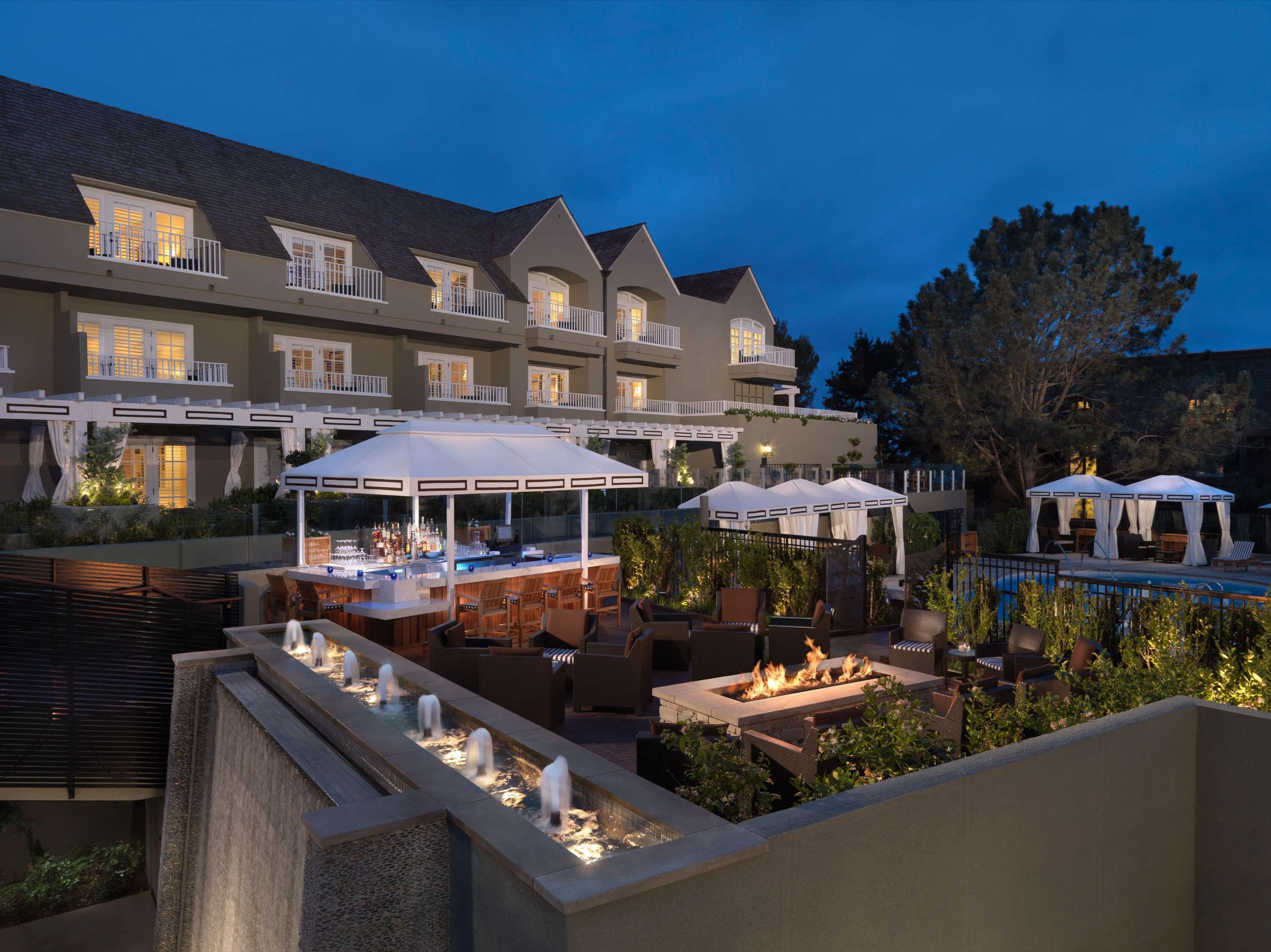 A hotel patio with outdoor seating, a bar, and a pool.