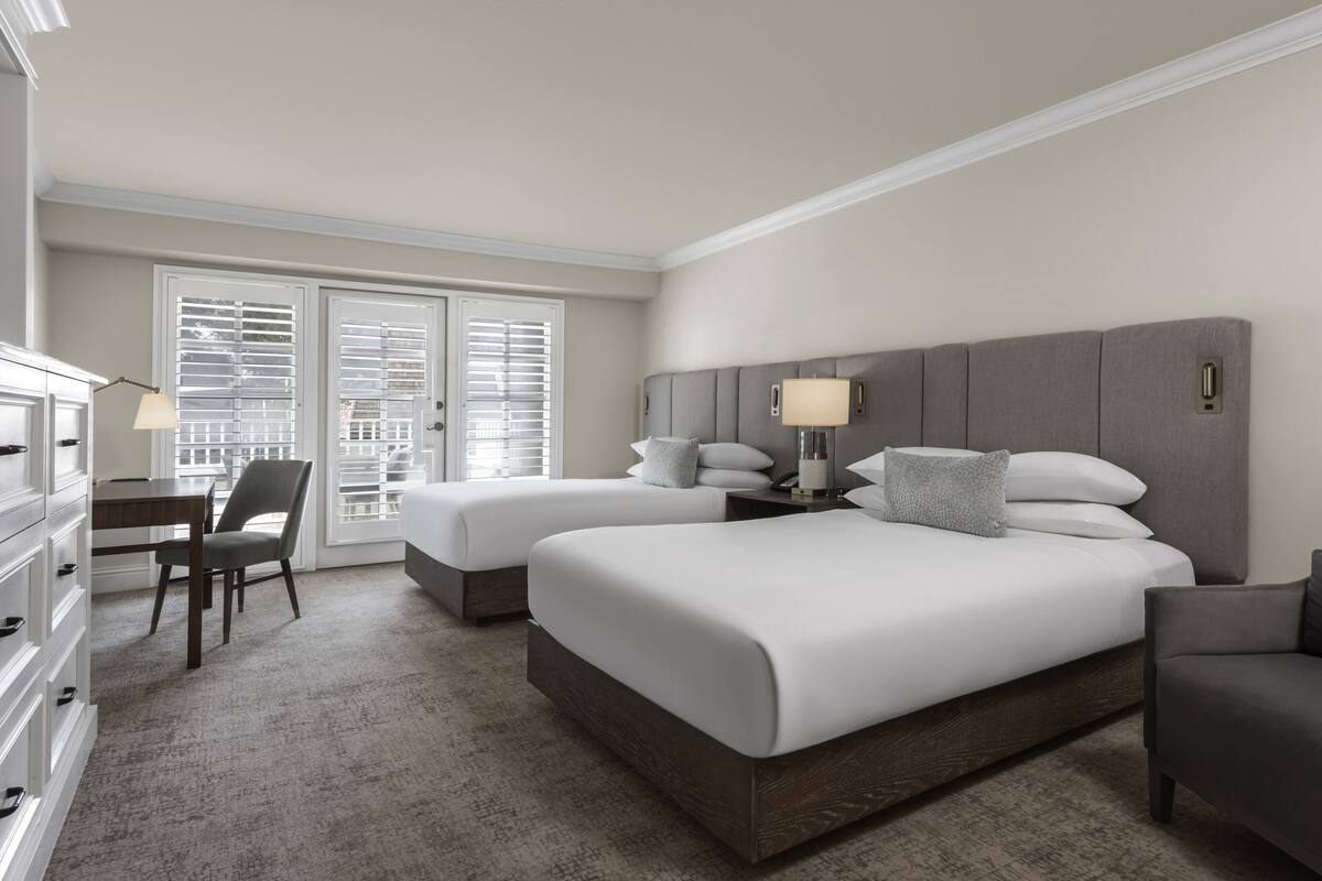 Habitación de hotel con dos camas, un escritorio y una silla.