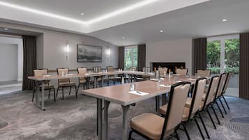 Ein Konferenzraum mit langem Tisch, Stühlen, einem Kamin und großen Fenstern.