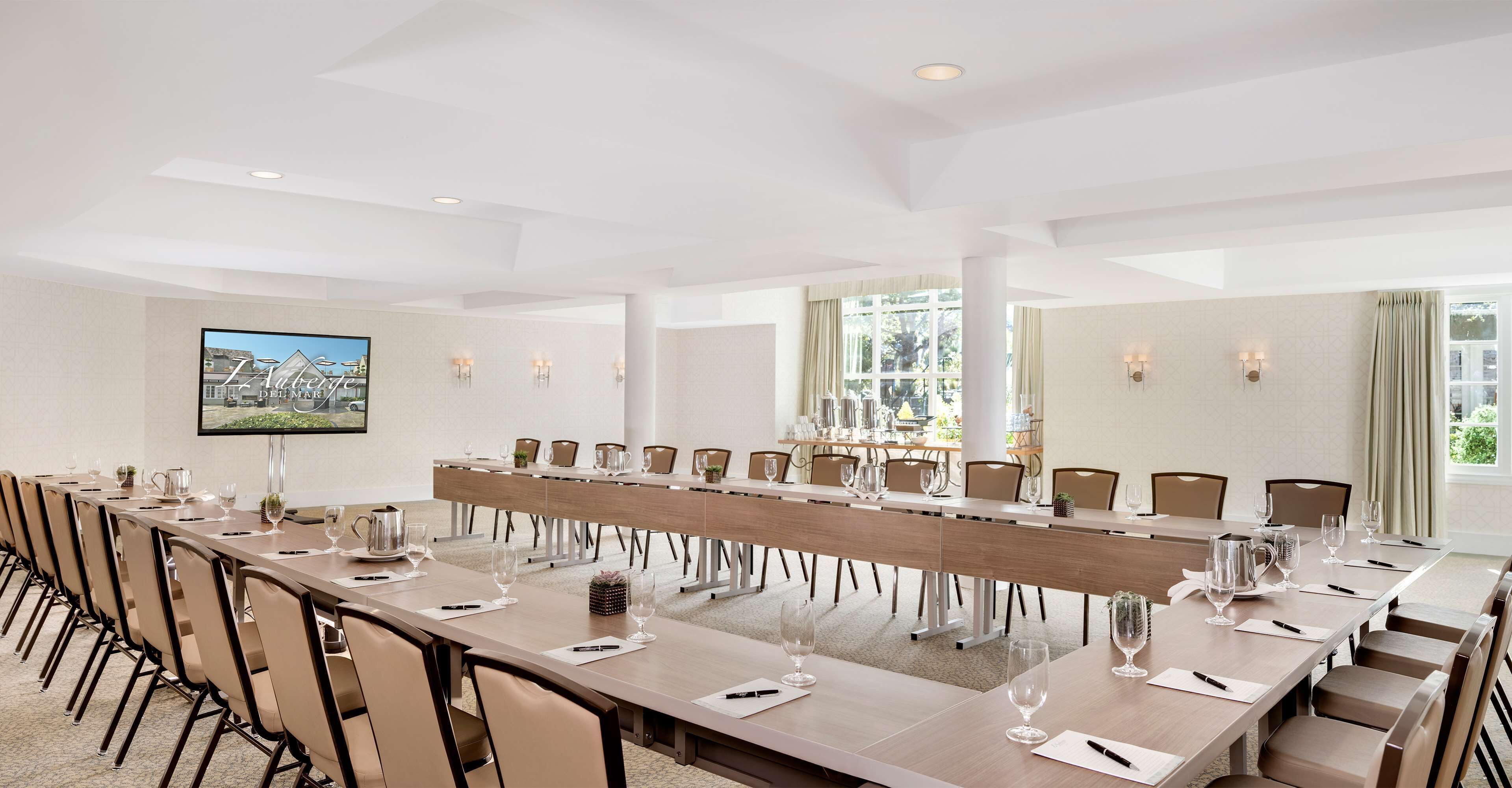 Un salón de conferencias con una mesa larga, sillas y un ventanal grande.