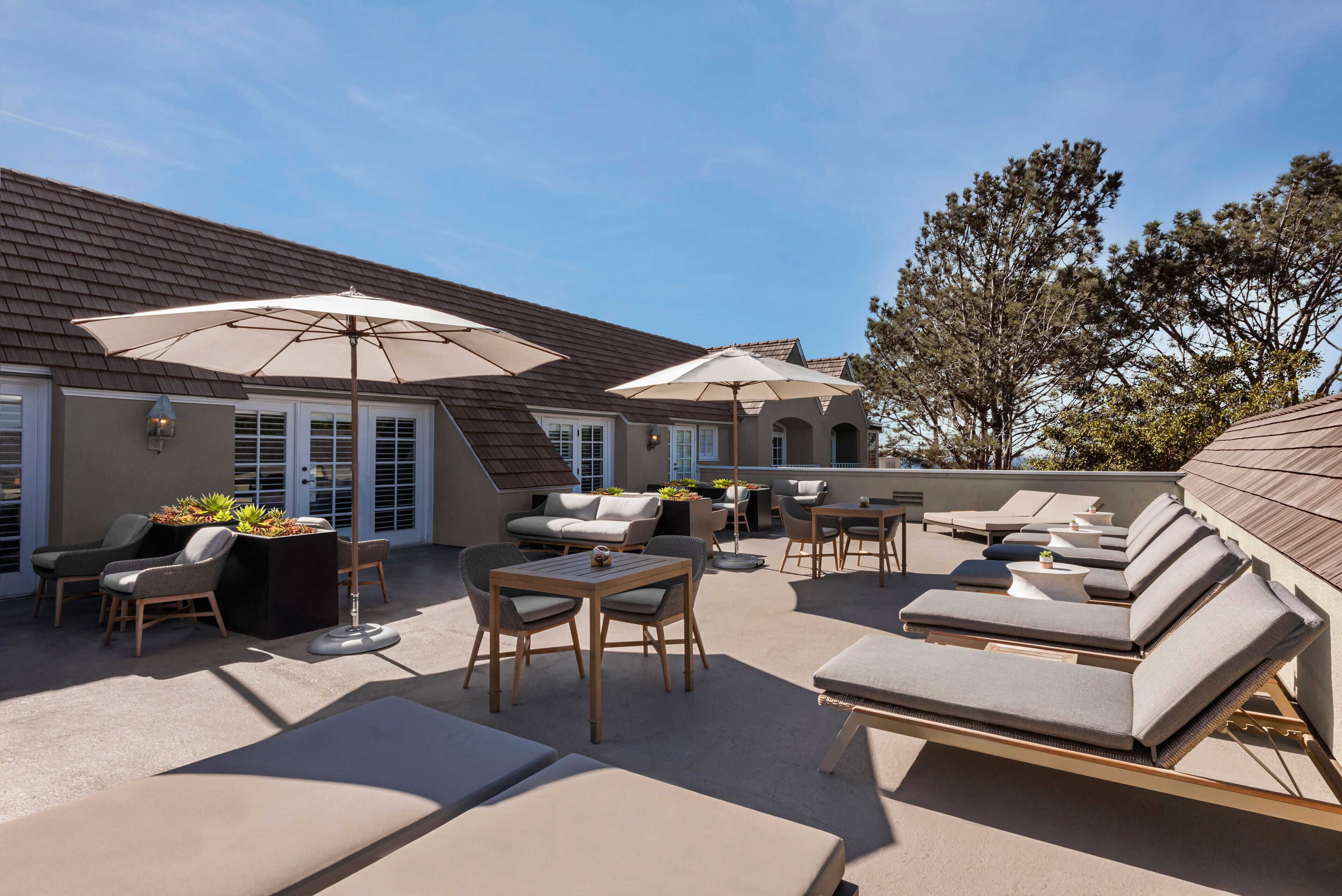 Eine Terrasse im Freien mit Lounge-Möbeln, einem Tisch und Sonnenschirmen.