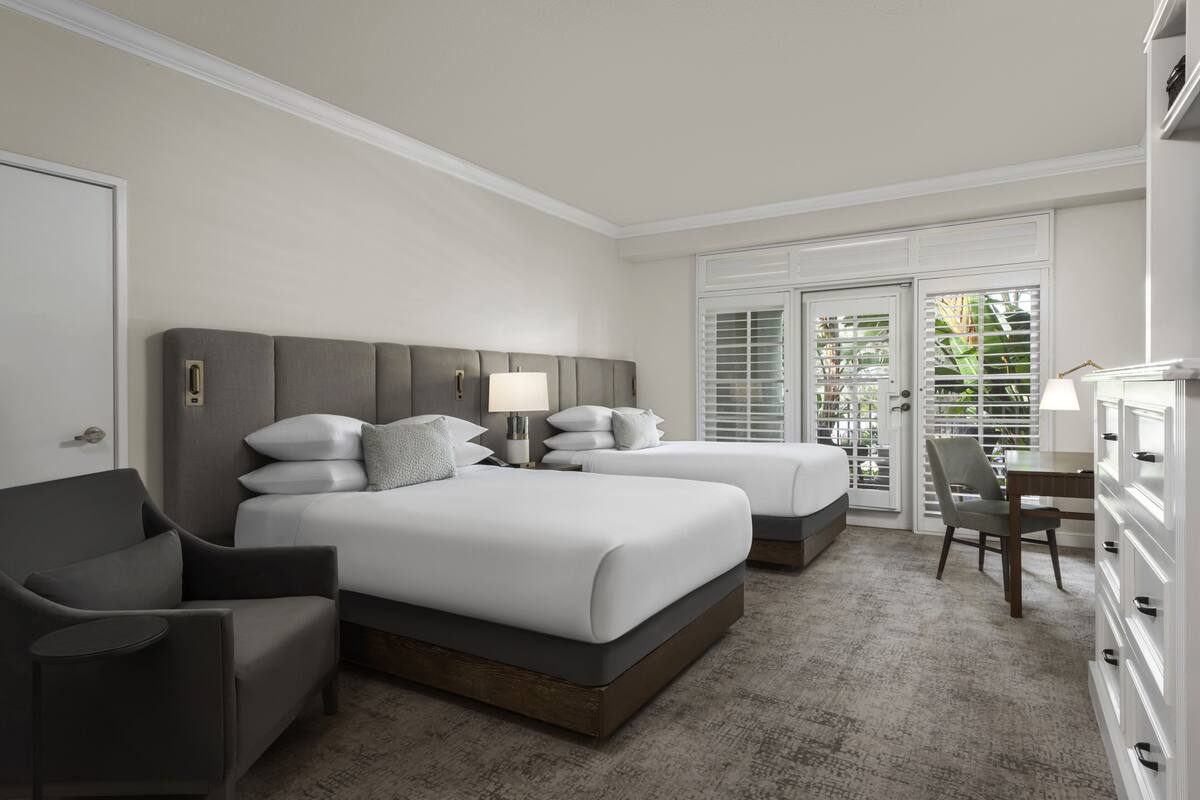 Habitación de hotel con dos camas, un escritorio y una silla.