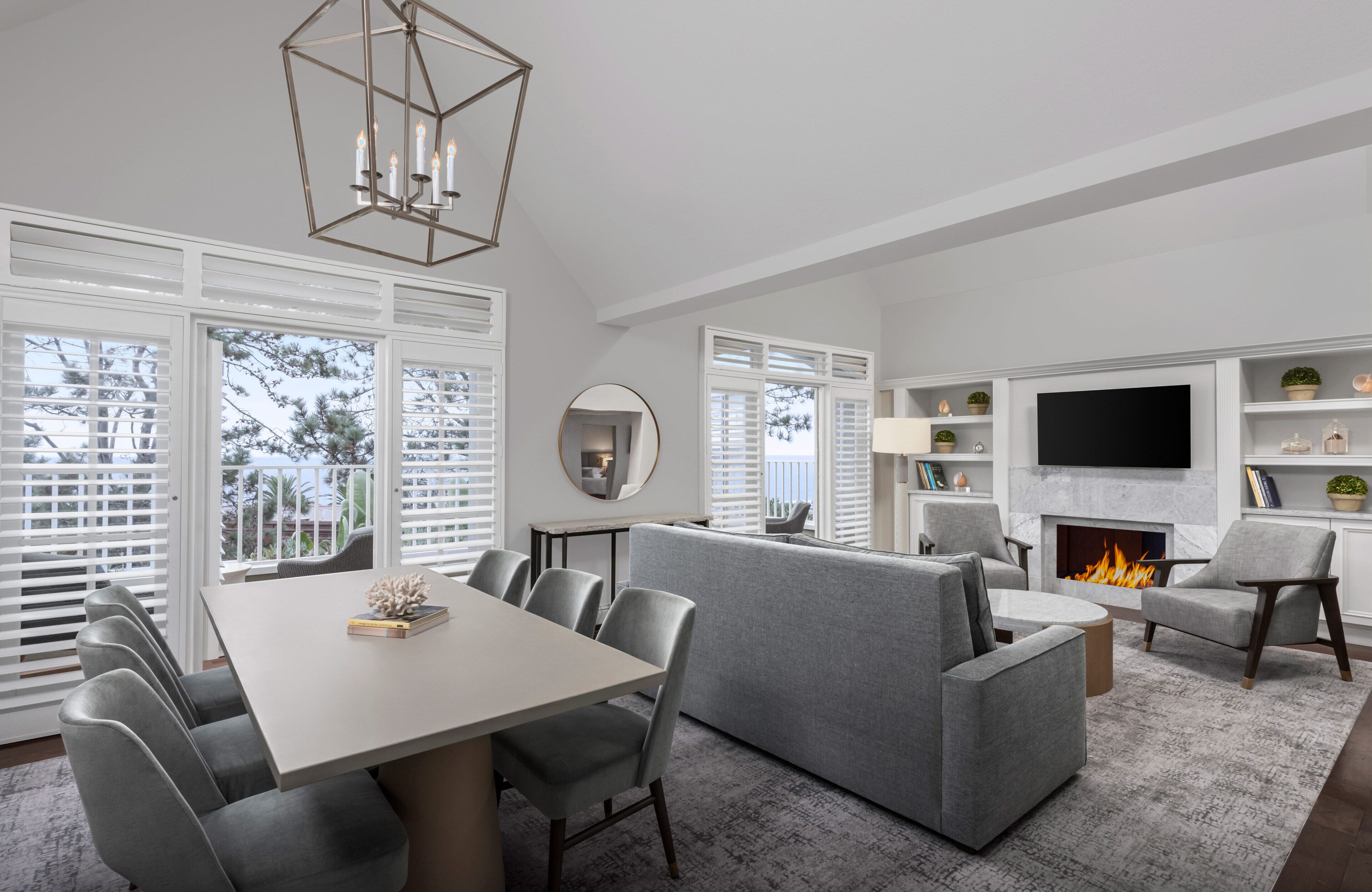 A modern living room with a fireplace, a dining area, and a TV wall unit.