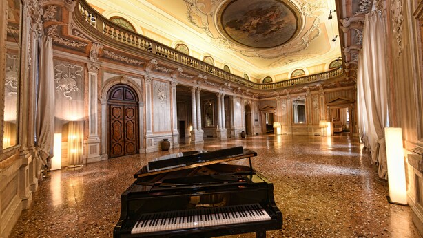 A grand hall with a grand piano, ornate columns, and a high ceiling with intricate designs. - Hotel Monaco & Grand Canal (Venice)