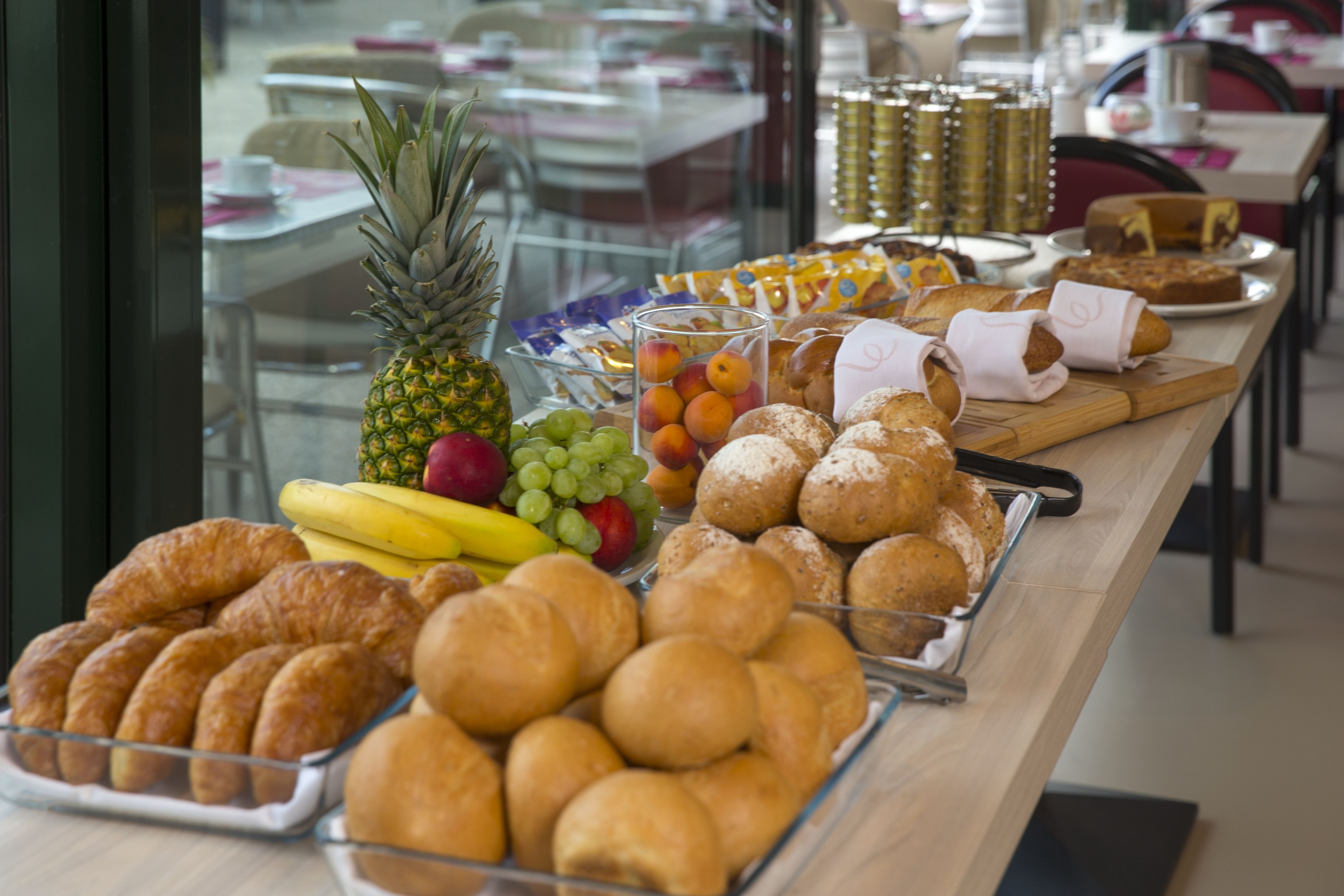 A buffet with various baked goods, fruits, and beverages.