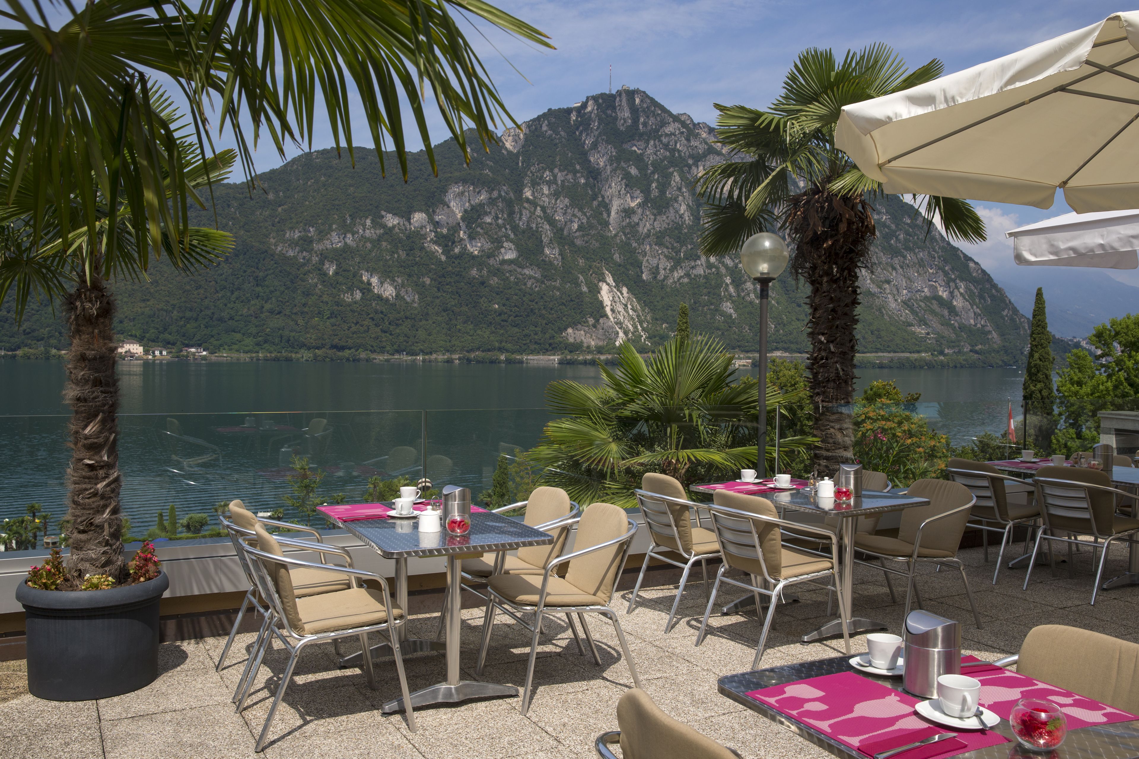 Un espace extérieur aménagé pour les repas, avec des tables et des chaises, offrant une vue sur un lac et des montagnes.