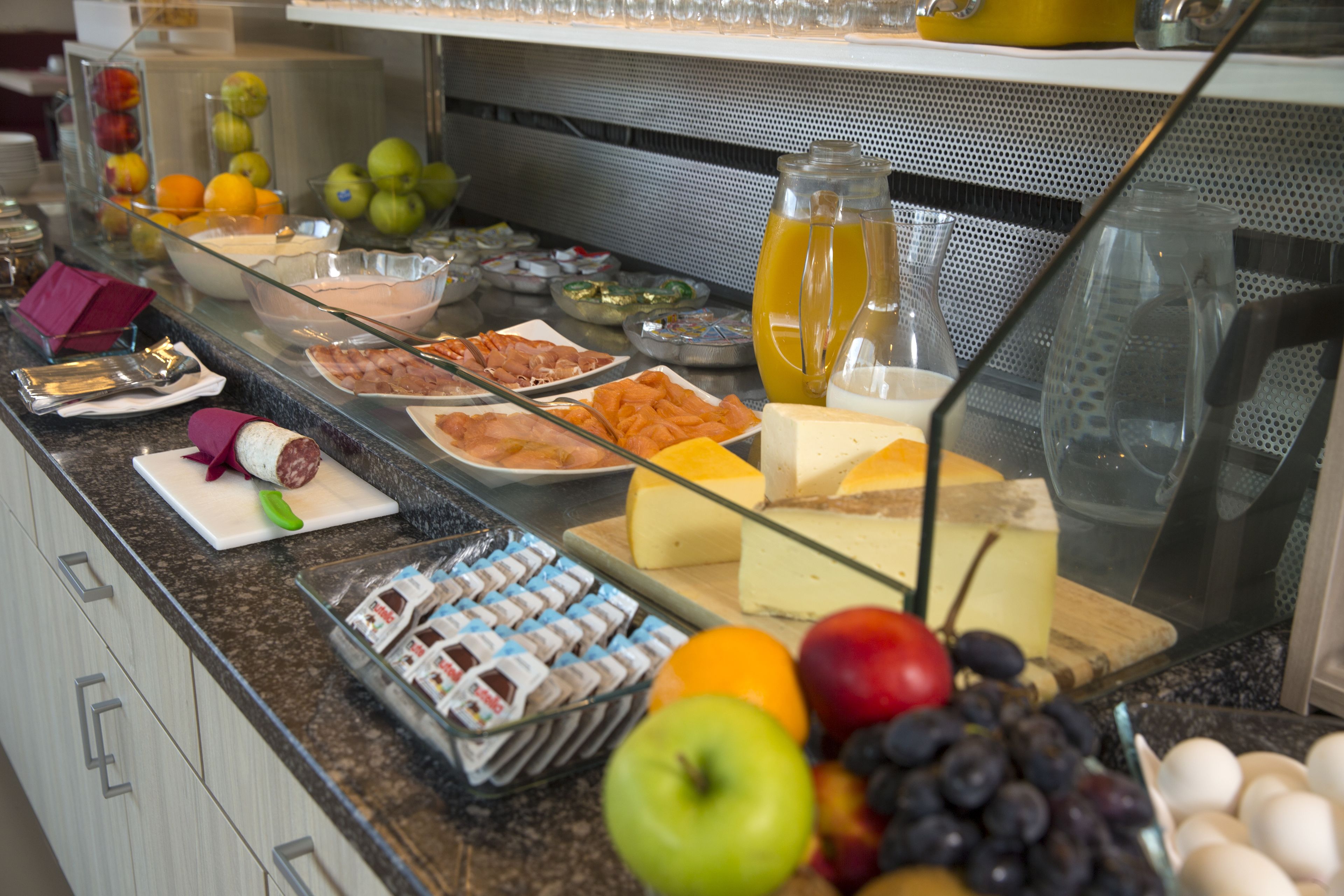 A buffet with various food items including fruits, cheeses, and meats.