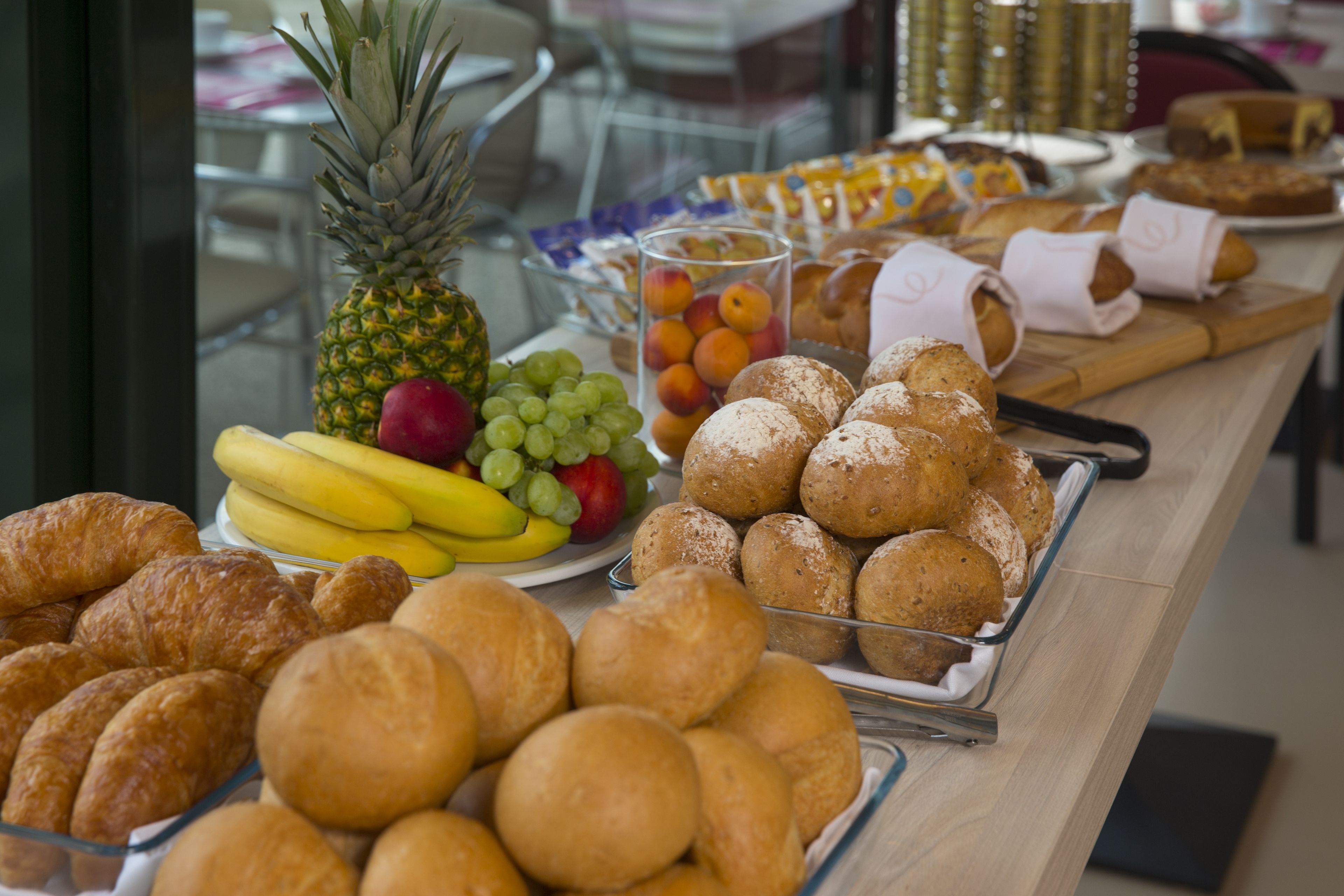 A buffet table with various baked goods, fruits, and pastries.