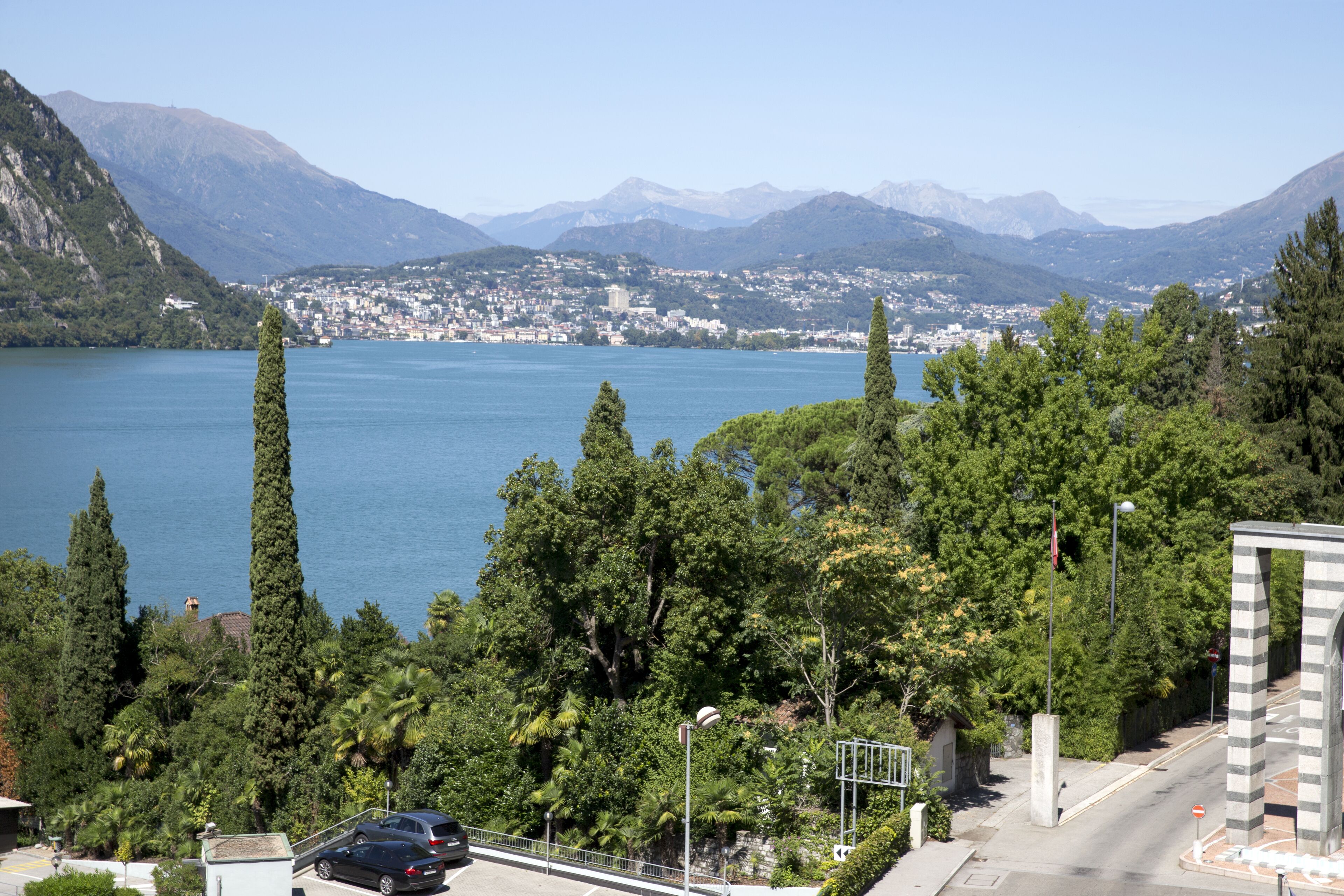 Un lac bordé de montagnes, entouré d’arbres et de quelques bâtiments.