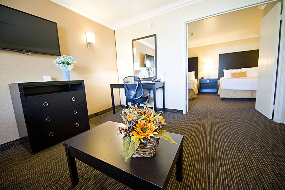 A hotel room with a flat-screen TV, a desk with a chair, a bed, and a bathroom visible through an open door.