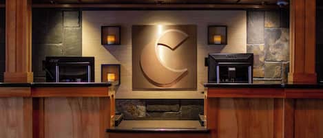 A reception area with a stone wall, a large clock, and two coffee machines.