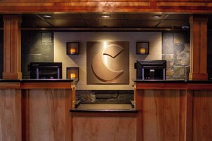 Zona de recepción con pared de piedra, un reloj grande y dos máquinas de café.
