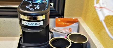 A reusable tray with a coffee maker, two cups of black tea, and a packet of tea.