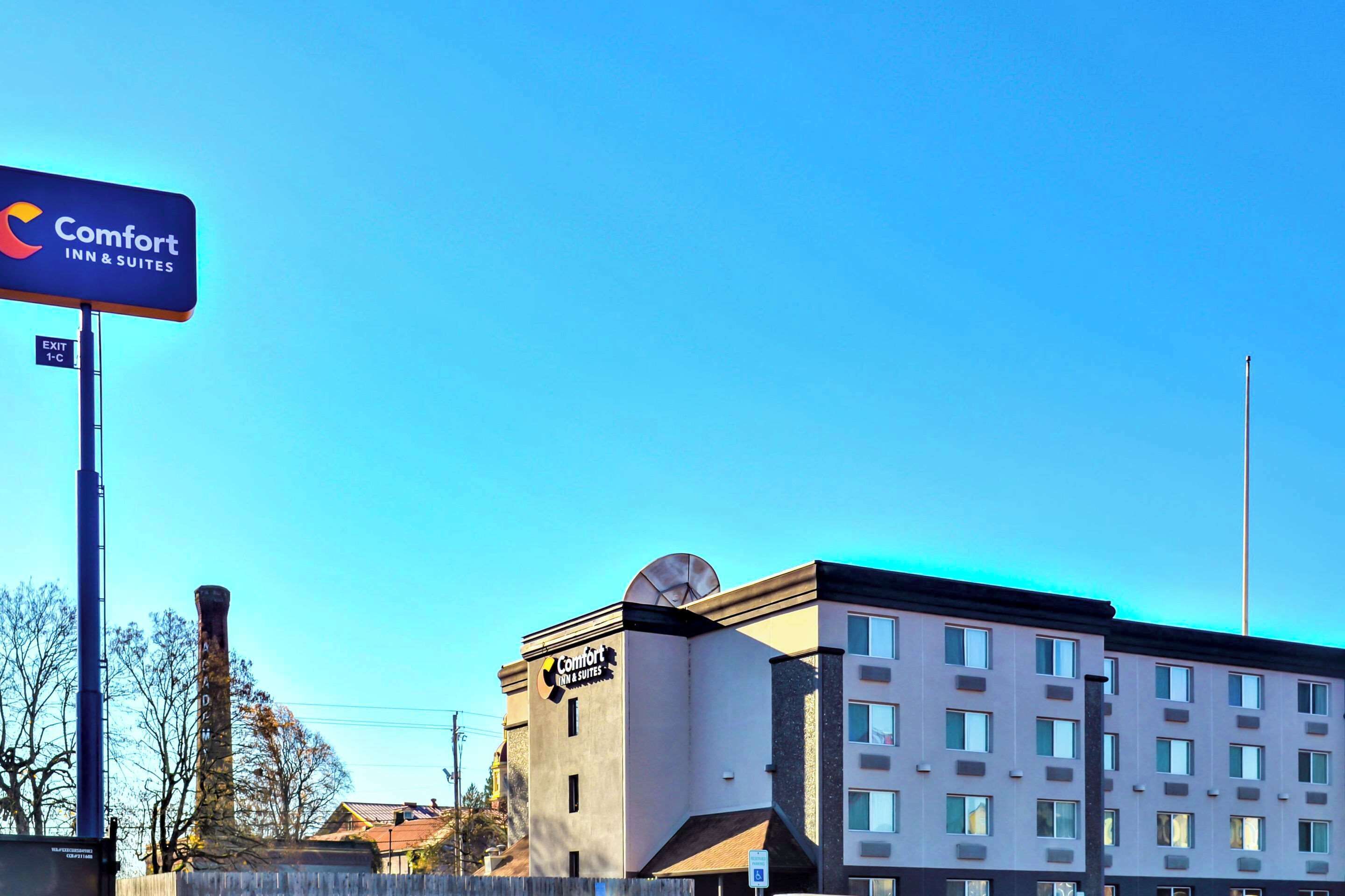 A Comfort Inn & Suites hotel with a modern design, featuring a prominent sign and a clear blue sky.