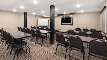 A conference room with multiple tables and chairs, a whiteboard, and a TV screen.