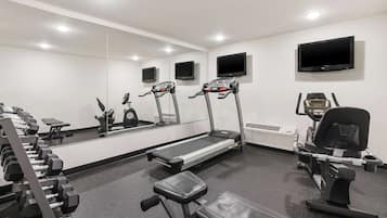 Un gimnasio con cintas de correr, mancuernas y máquinas de pesas.