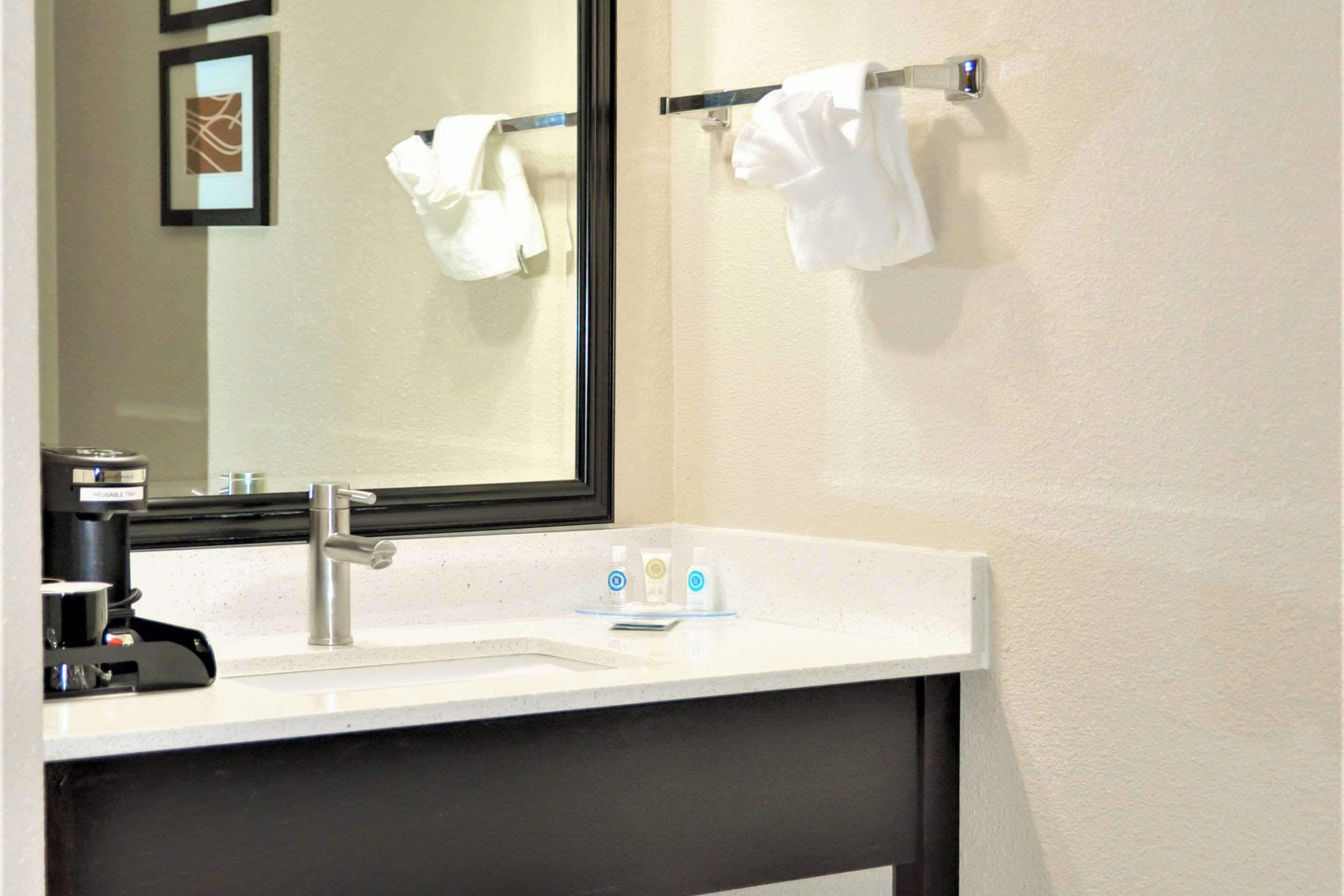 A hotel bathroom with a white sink, a mirror, and two towels hanging on a towel rack.