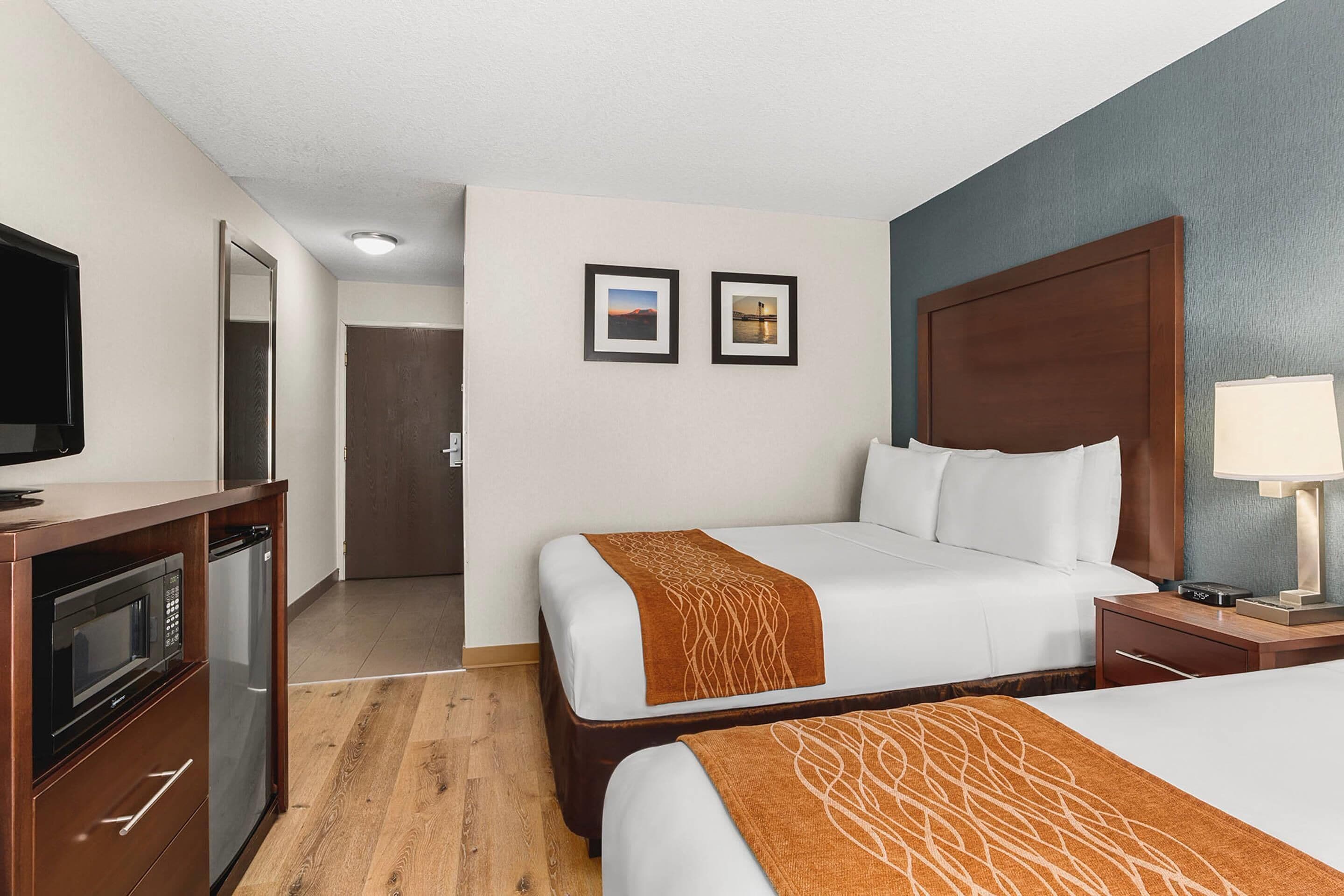 Habitación de hotel con dos camas, televisión, microondas y lámpara.
