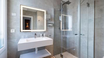 A modern bathroom with a large mirror, white sink, and glass shower enclosure.