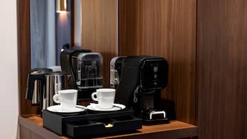 Una estación de café con dos tazas blancas y una máquina de café sobre una encimera de madera.