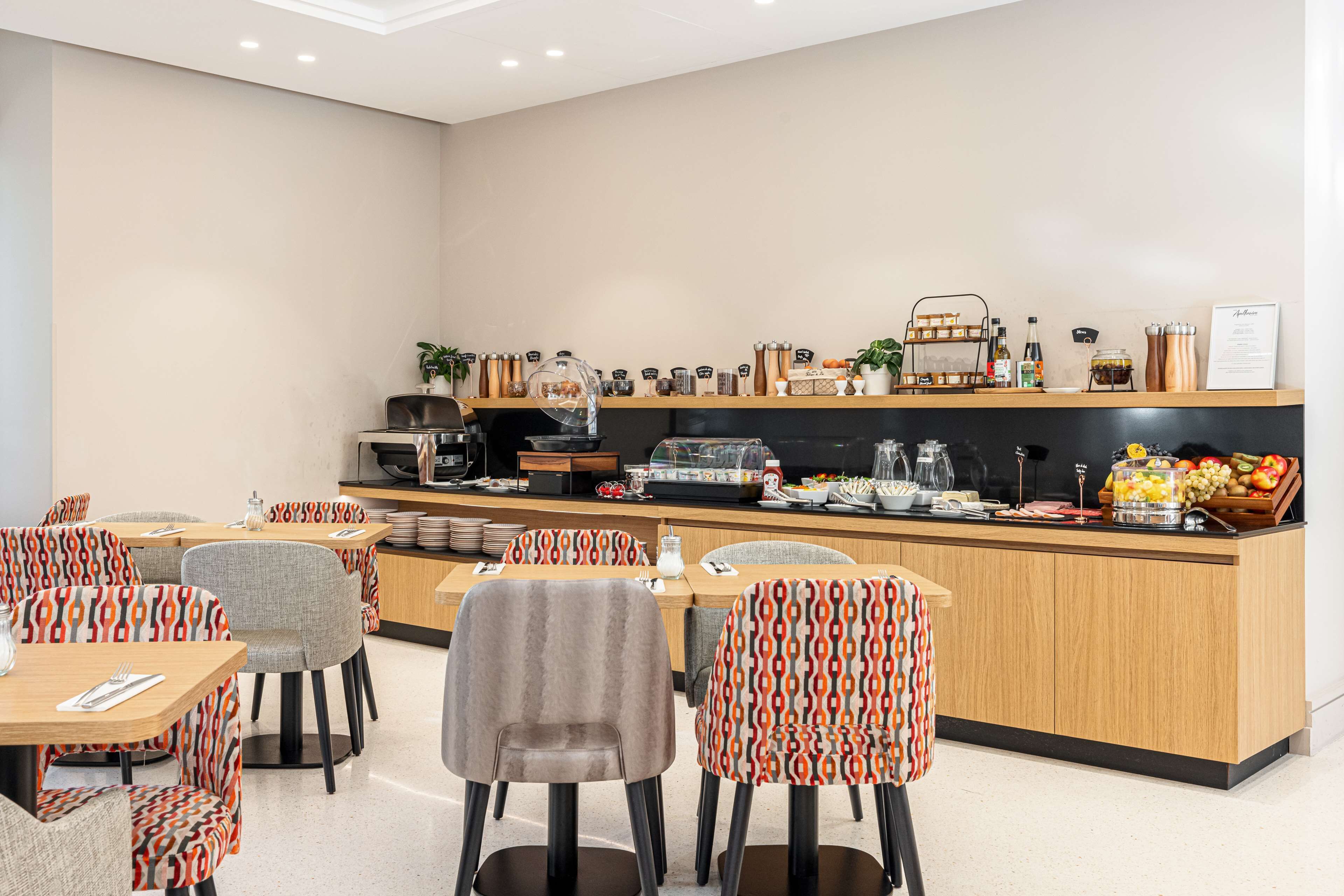 A modern cafe with a central counter, seating area, and various food and drink items.