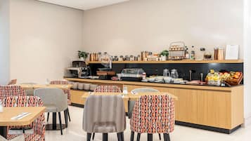 A modern cafe with a central counter, seating area, and various food and drink items.