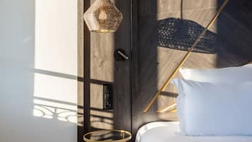 Un dormitorio moderno con puerta de madera, una mesita de noche redonda, una cama blanca y una lámpara colgante.