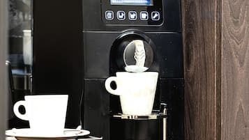 Una cafetera con pantalla digital, una taza y una bandeja.