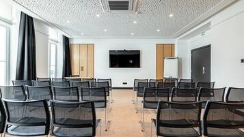 A conference room with rows of chairs, a large screen, and a whiteboard.