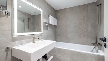 Un baño moderno con un espejo grande, dos lavamanos, una bañera y una ducha.