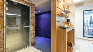 Un baño moderno con cabina de ducha de vidrio, pared de acento azul oscuro y tocador de madera con cesta.