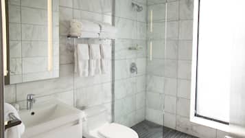 A modern bathroom with a white sink, toilet, and glass-enclosed shower.