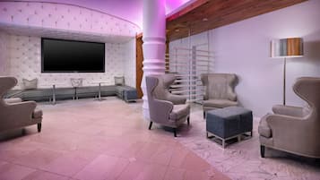 Un moderno salón con un televisor de pantalla plana grande, asientos confortables y una estructura de columna original.
