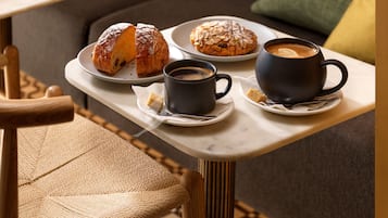 Uma bandeja com um croissant, um muffin e duas xícaras de café sobre uma mesa.