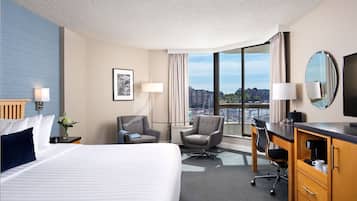 Une chambre d’hôtel avec un grand lit, un bureau, une chaise, une télévision et une vue sur la ville.