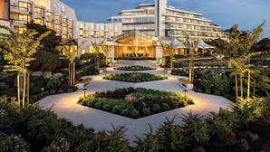 A modern hotel with a central courtyard, multiple balconies, and a well-lit entrance.