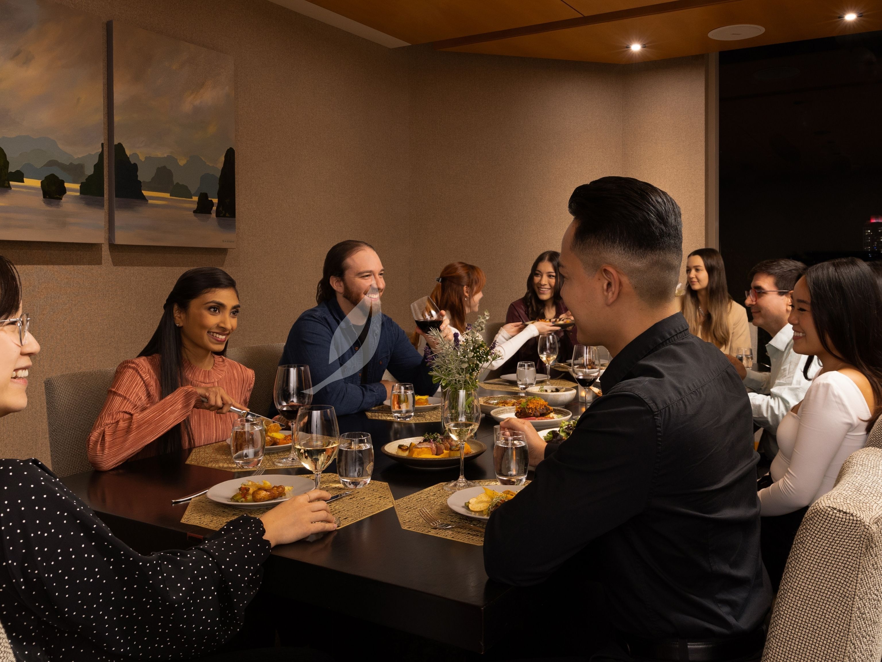 A group of people dining at a table with various dishes and drinks.