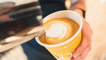 A person holding a cup of coffee with latte art.