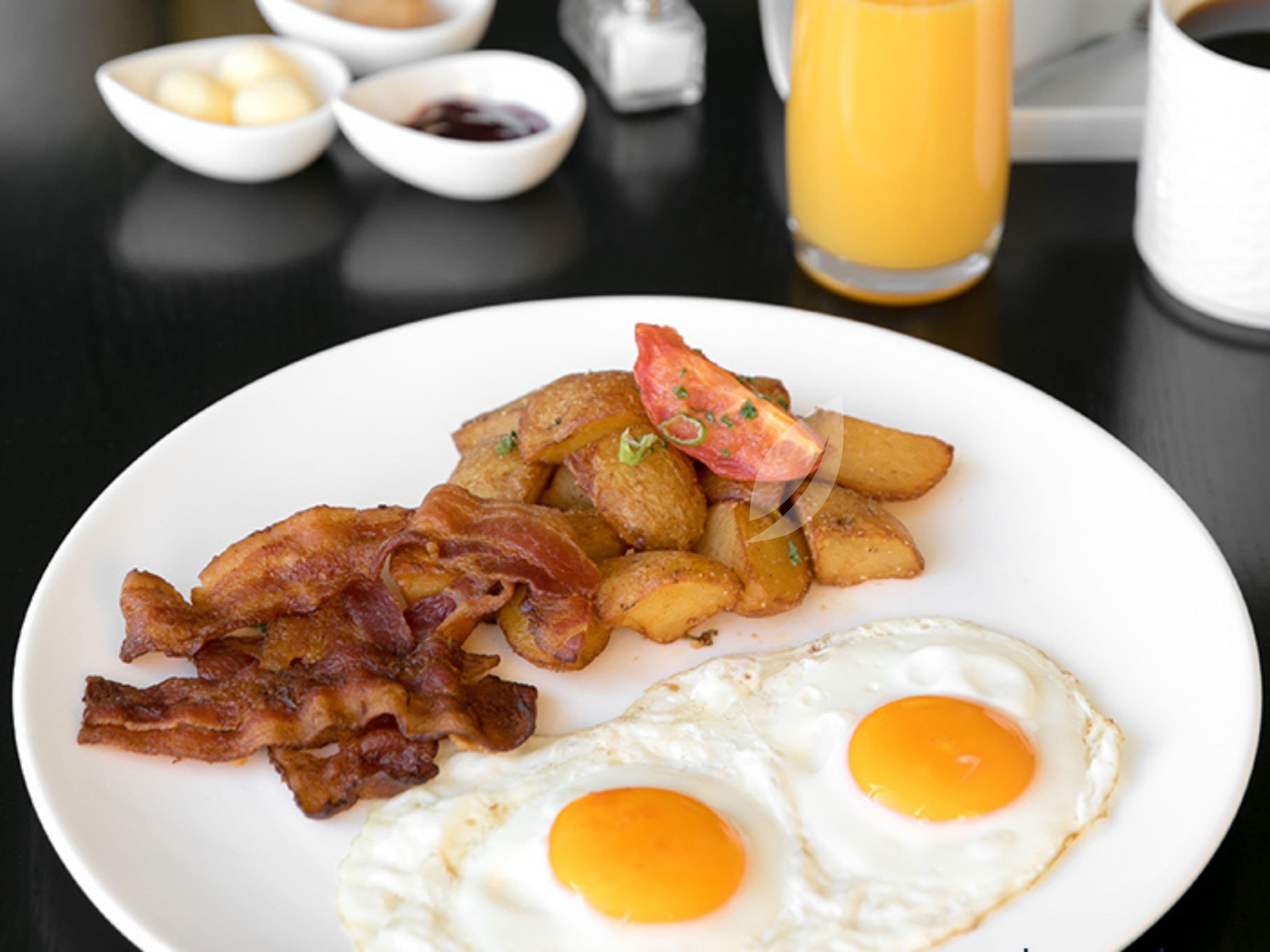 A breakfast plate with bacon, eggs, and potatoes.