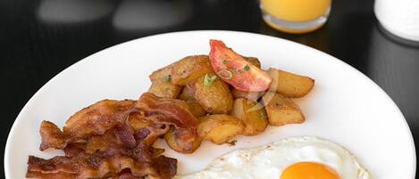A breakfast plate with bacon, eggs, and potatoes.