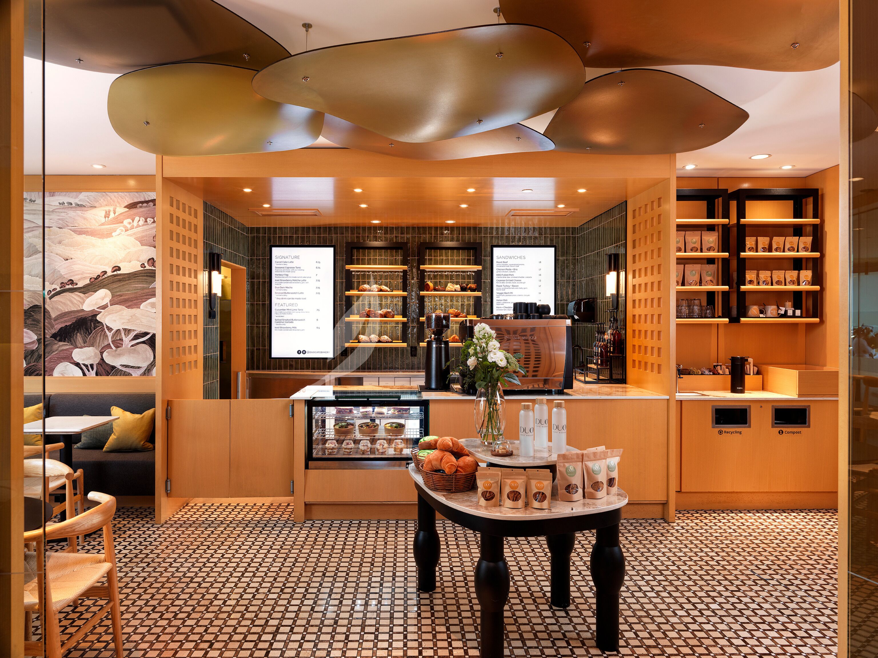 L’intérieur d’un café, avec un tableau affichant le menu, un espace réservé aux clients et un présentoir de pâtisseries.