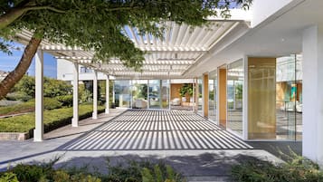 Une terrasse extérieure moderne avec un sol à motifs, des portes vitrées et une pergola blanche.