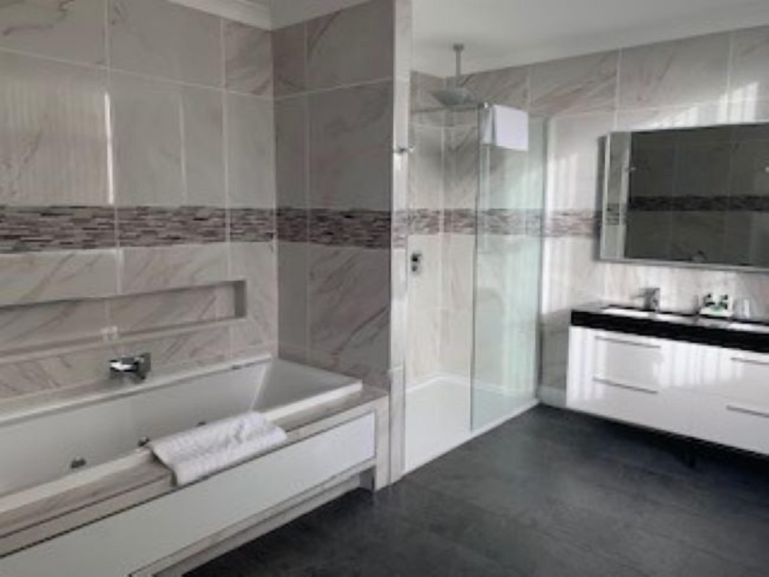 A modern bathroom with a freestanding bathtub, a glass shower enclosure, and a large mirror above the vanity.