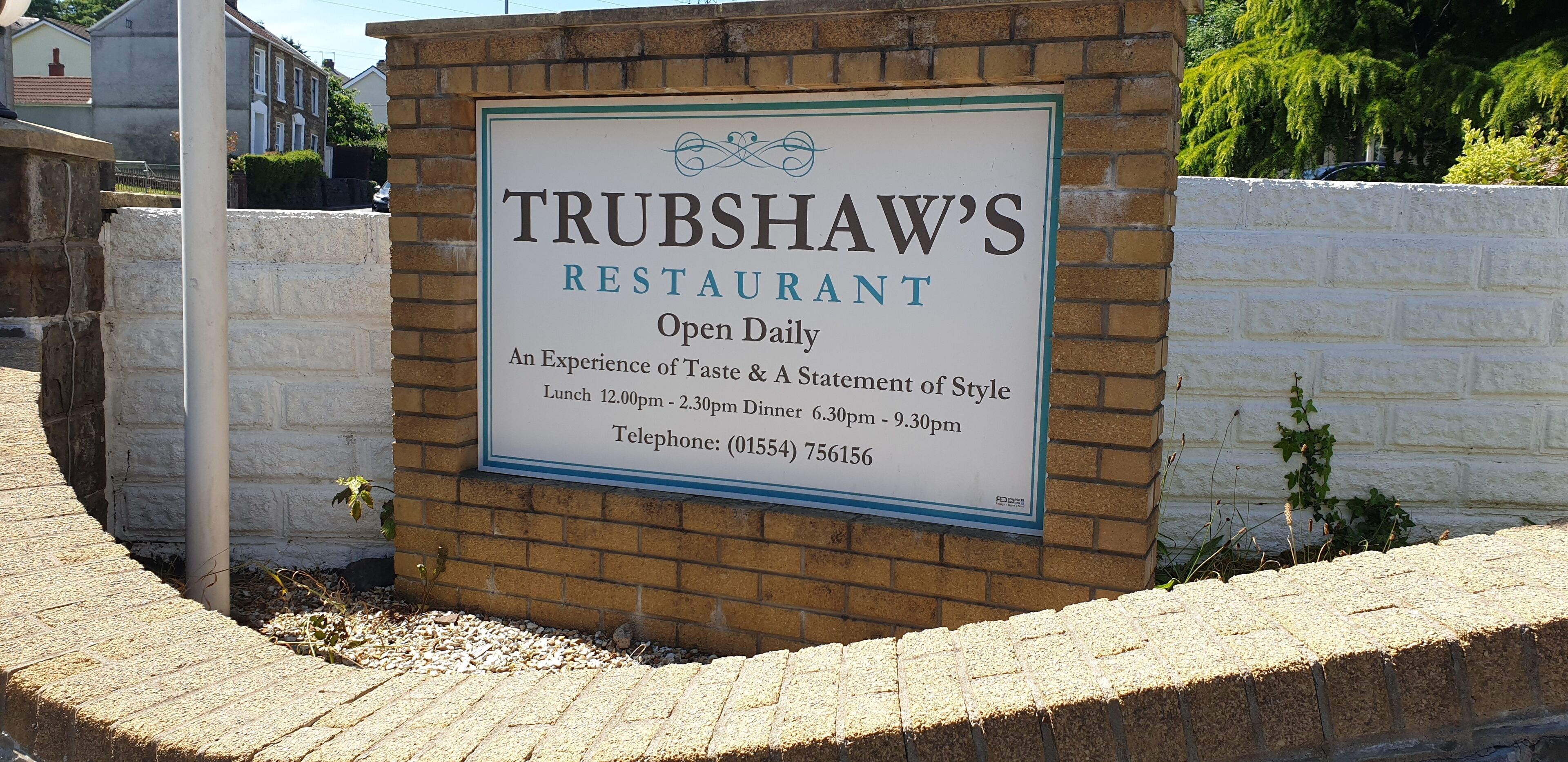 A sign for Trubshaw's Restaurant, indicating it is open daily with lunch and dinner hours listed, and a telephone number provided.
