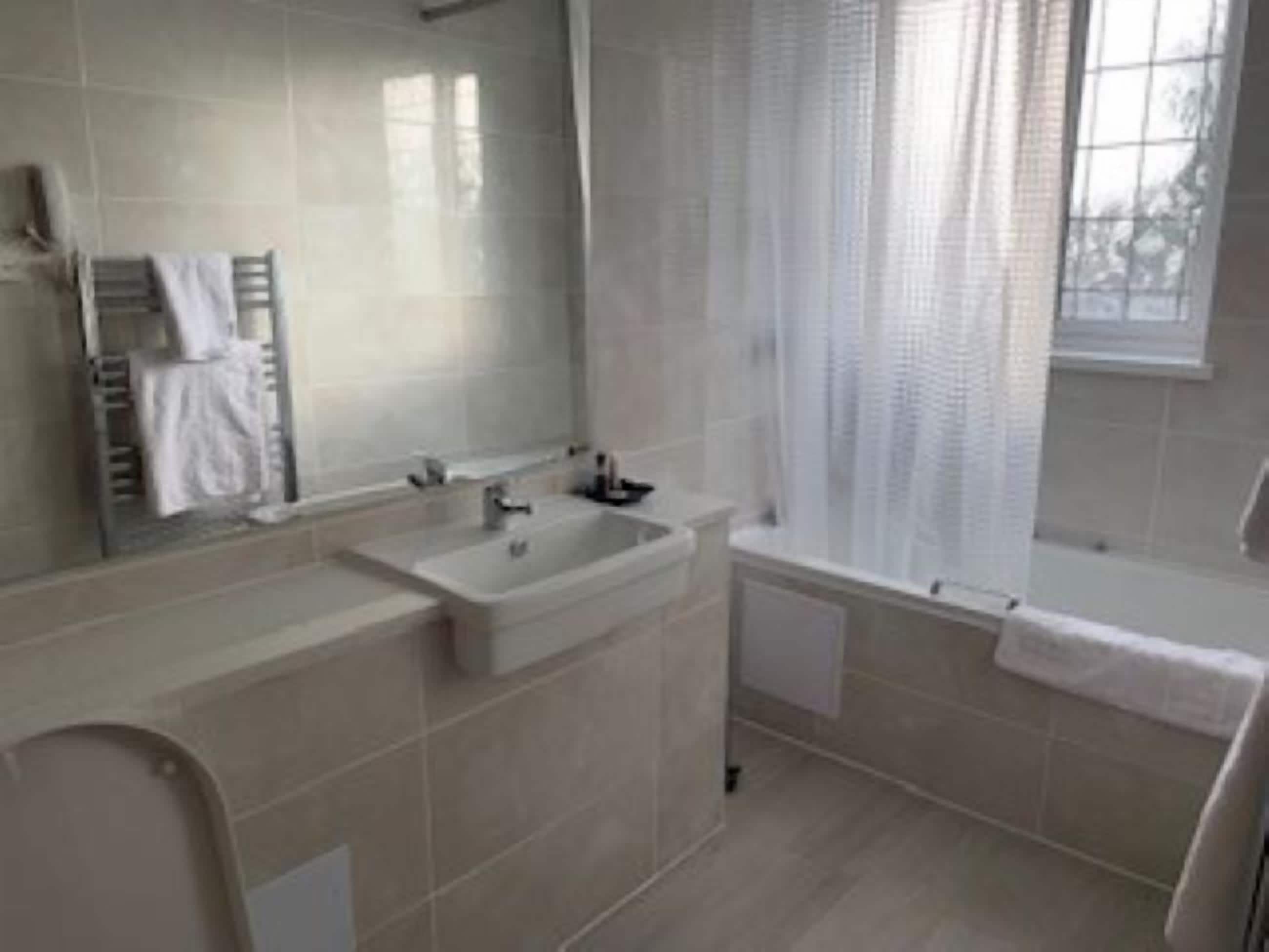 Ein modernes Badezimmer mit einem großen Waschbecken, einem Spiegel und einer Badewanne.