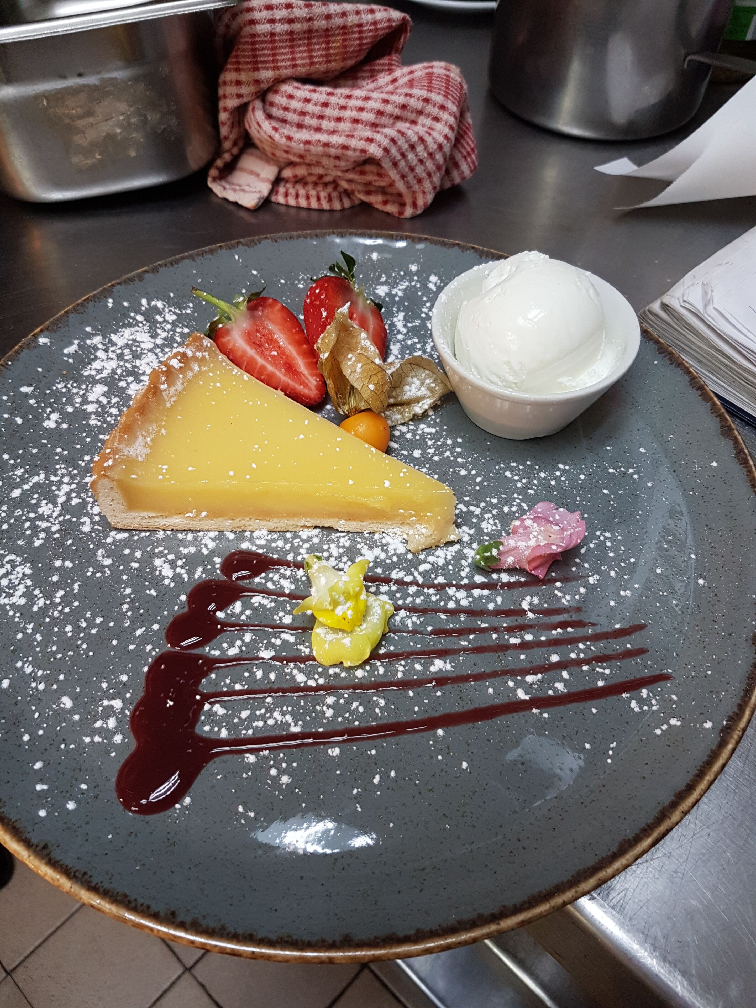 A dessert plate with a slice of pie, strawberries, a small bowl of ice cream, and chocolate sauce.