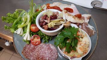 A plate of food with various items including sliced salami, a salad, and a bowl of beans.